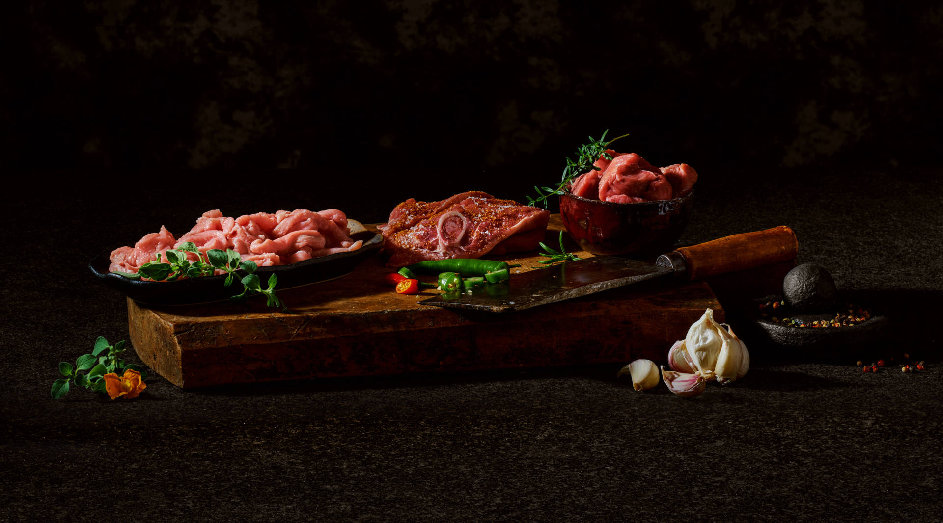 Fleisch, Gewürze und ein Messer auf einem Holzbrett